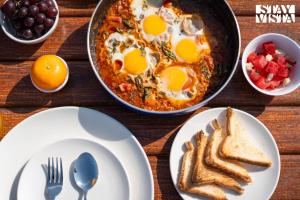 a table topped with plates of food with eggs and toast at StayVista at Blisswood Cottage with Pool & Bar in Nashik