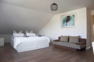 a white bedroom with a bed and a couch at Ferienwohnung-Milena in Gundelfingen an der Donau