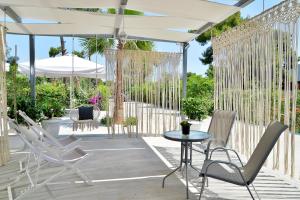 a patio with white chairs and a table and an umbrella at Alekos Luxury Suites - Free 24hr Transformation From To Airport in Artemida