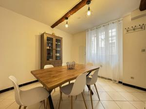 una sala da pranzo con un tavolo di legno e sedie bianche di Chambre Saint-Nazaire 3e Etage a Béziers