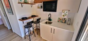 a small kitchen with a sink and two stools at A Casiña Laranxa in Cangas de Morrazo