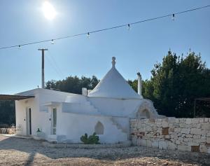 a white church with a white roof and a wall at Trullo Moi in Ostuni