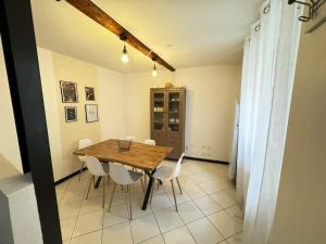 a dining room with a wooden table and white chairs at Chambre Orb 1 etage in Béziers
