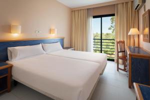 a bedroom with a large white bed and a balcony at Sol Sancti Petri Aparthotel in Chiclana de la Frontera +62 photos