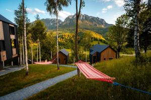 un'amaca in un campo con case e montagne di Mountain Escape Resort a Zărneşti