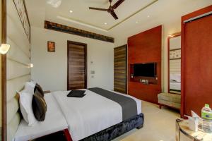 a bedroom with a large bed and a television at Super Townhouse Oak Hotel C Pearls in New Delhi
