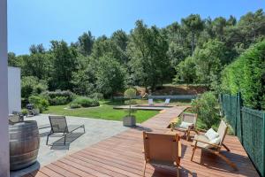 a backyard with a wooden deck with chairs and a barrel at Lou Souvarel - Maison au calme proche calanques in Roquefort-la-Bédoule