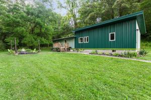 a green building with a yard in front of it at Frog Hollow at Hocking Vacations in Logan