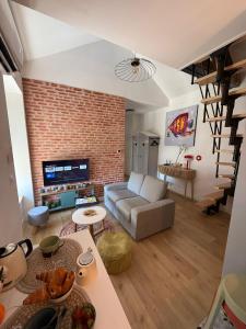 a living room with a couch and a brick wall at Maison Sorbier - Appartement 2 in Nevers