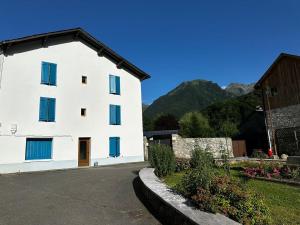 a white building with blue windows and mountains in the background at Studio 3 Aux volets bleus in Aulus-les-Bains