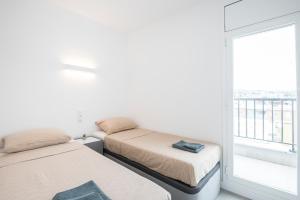 two beds in a room with a window at Marina View Penthouse in Calafell