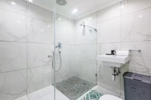 ダーバンにあるThe Green Diamond - Stylish and Spacious Umhlanga Ridge Apartment - Rooftop Pool and King Bedsのシャワーと洗面台を備えた白いバスルーム