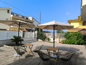 two tables and chairs with umbrellas on a patio at Villa Topaz iun T4815 in Capoterra