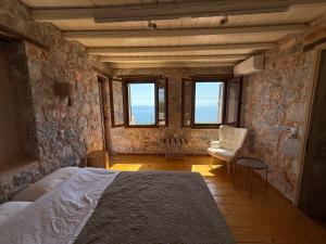 a bedroom with a bed and a chair and windows at Pirgos Petropoulea in Poliána