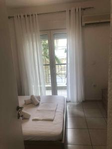 a bedroom with a bed and a large window at Miminllari APARTMENTS 2 in Pefkohori