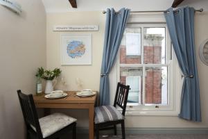 einem Esstisch mit 2 Stühlen und einem Fenster in der Unterkunft Bessie Ellens Cottage in Fowey