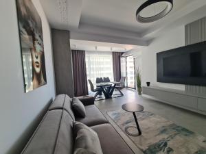 a living room with a couch and a television at Residence Sole by Axxis Nova Resort - Apartament luxury 70mp cu terasa si vedere la mare, acces direct pe plaja Axxis Beach BluFlag - Mamaia Nord - Parcare gratuita in Mamaia