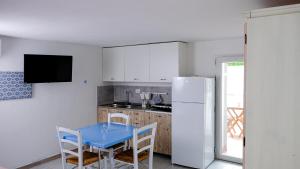 a kitchen with a blue table and a refrigerator at Rooms Apartaments Santa Teresa in Capo Testa