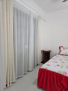 una camera da letto con tende bianche, un letto e una finestra di Apartamento em Cabo Frio a Cabo Frio