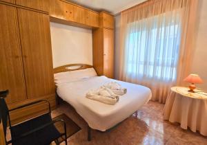 Un dormitorio con una cama con toallas blancas. en Apartamento Las Olas Santa Pola, en Santa Pola