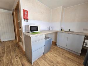 a kitchen with white cabinets and a microwave on a counter at The Albert Hotel in Gloucestershire