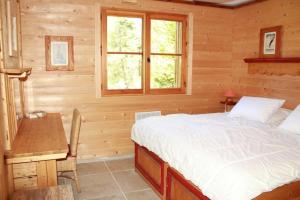 a bedroom with a bed and a desk and a window at L'Evasion Authentique - Nature & Cheminée in Les Thuiles