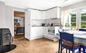 a kitchen with white cabinets and a table and chairs at Hundevennlig feriehus ved sjøen på Geisnes in Sørmoen