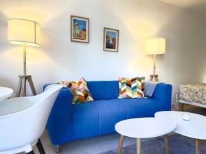 a living room with a blue couch and tables at Spacious new studio and terrace in Juan-les-Pins