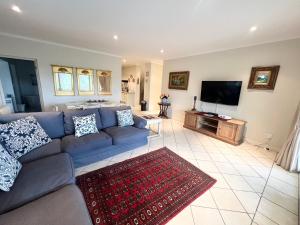 a living room with a blue couch and a flat screen tv at Golfers paradise on 25th green in Hermanus