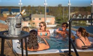 um grupo de mulheres em uma banheira de hidromassagem com uma garrafa de vinho em Hotell Hulingen em Hultsfred