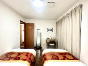 een hotelkamer met twee bedden en een bureau bij 花の郷田端a04 in Tokyo