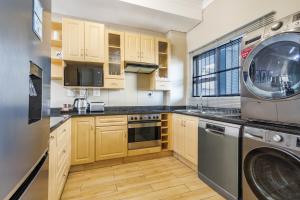 una cucina con armadi in legno, lavatrice e asciugatrice di Elegant Emerald Stay at Ridgeton Modern Two Bedroom Apartment in the Heart of Umhlanga Ridge Sleeps 6 a Durban