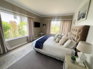 a bedroom with a large bed and a large window at Golfers paradise on 25th green in Hermanus