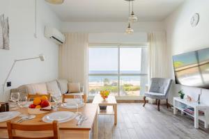a living room with a table and a couch at GW212 Gugel Waves Amazing Seaview Pool Apartments in Nahariyya