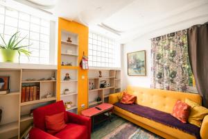 a living room with a yellow couch and red chairs at Easy Stay Apartments in Pristina