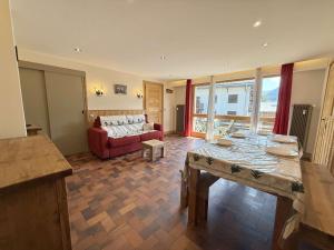 a living room with a table and a red couch at Appartement cosy au cœur de Praz-Sur-Arly - 5 pers, proche centre et pistes, parking et casier ski - FR-1-603-35 in Praz-sur-Arly +12 photos