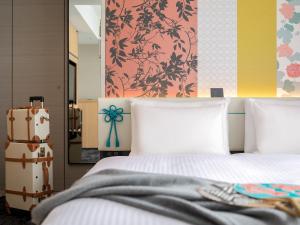 a bedroom with a bed with white sheets and a suitcase at Mitsui Garden Hotel Kyoto Shijo in Kyoto +36 photos