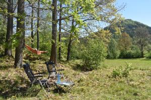 two chairs and a table in a field with trees at Domek Mobilny w Górach Sokolich in Karpniki +3 photos