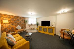 a living room with a yellow couch and a television at Cotswolds, 2Bed 1 Bath Historic Flat, Very Central in Cirencester