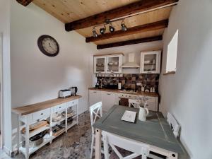 a kitchen with a table and a clock on the wall at Apartma Under The Drunk Railroad in Kozljak +7 photos