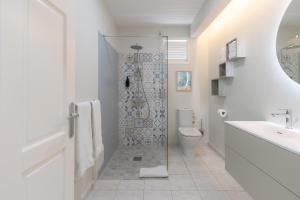 Un baño blanco con ducha y WC. en Bel Embrun - Villa Iléenne, en Les Trois-Îlets