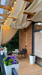 een patio met witte gordijnen, tafels en bloemen bij Darkhan Tau in Alma-Ata