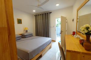 a bedroom with a bed and a desk and a mirror at Stay Kora in Thinadhoo