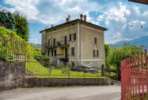 an old house with a red fence in front of it at Villa Pini Balbiani - Appartamento Pini in Lierna