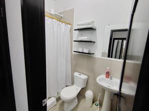 a white bathroom with a toilet and a sink at Refugio de Daye in Puerto Ayora