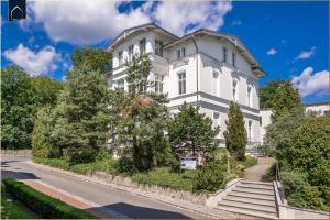 ein großes weißes Haus mit Bäumen vor einer Straße in der Unterkunft Villa Martha Apartment 3 in Heringsdorf