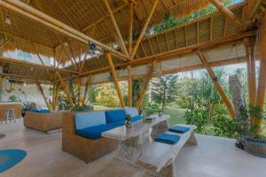 an outdoor living room with a blue couch and tables at Coco Verde Bali Resort in Tanah Lot