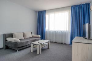 a living room with a couch and a tv at Лозенец Резорт in Lozenets