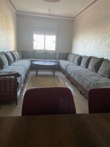a living room with a large couch and a table at Apparemment très bien équipé et Très propre Dans un bon emplacement in Tangier