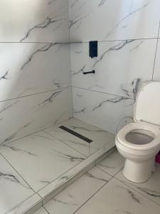 a white bathroom with a toilet and marble walls at Starehe Villa in Arusha